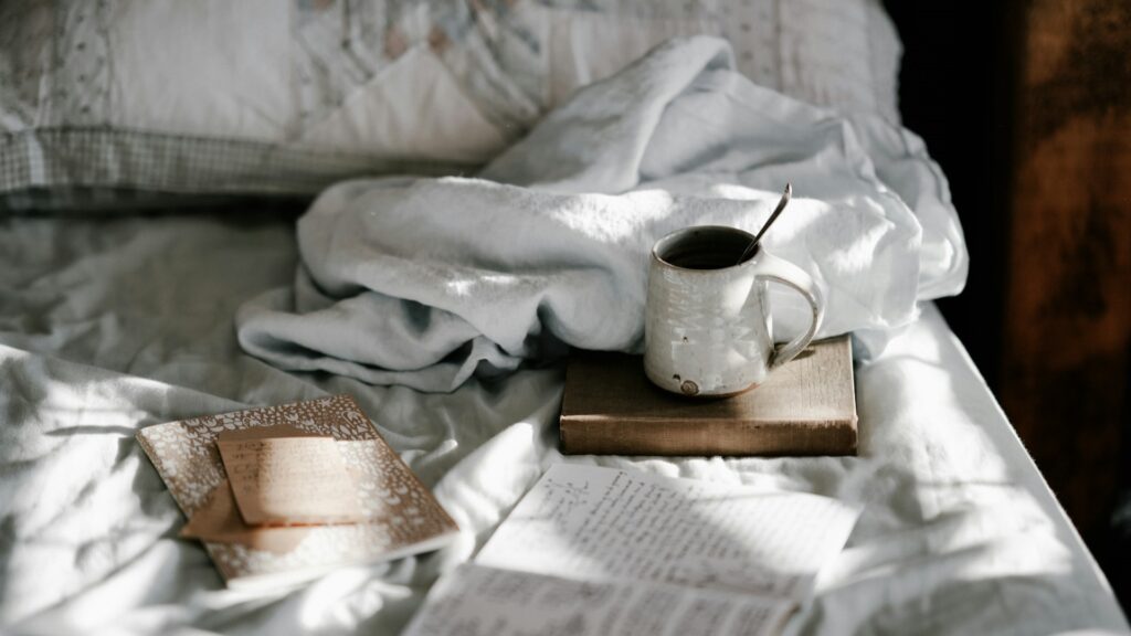 Comfort in bed met warme drank, notities en zacht ochtendlicht