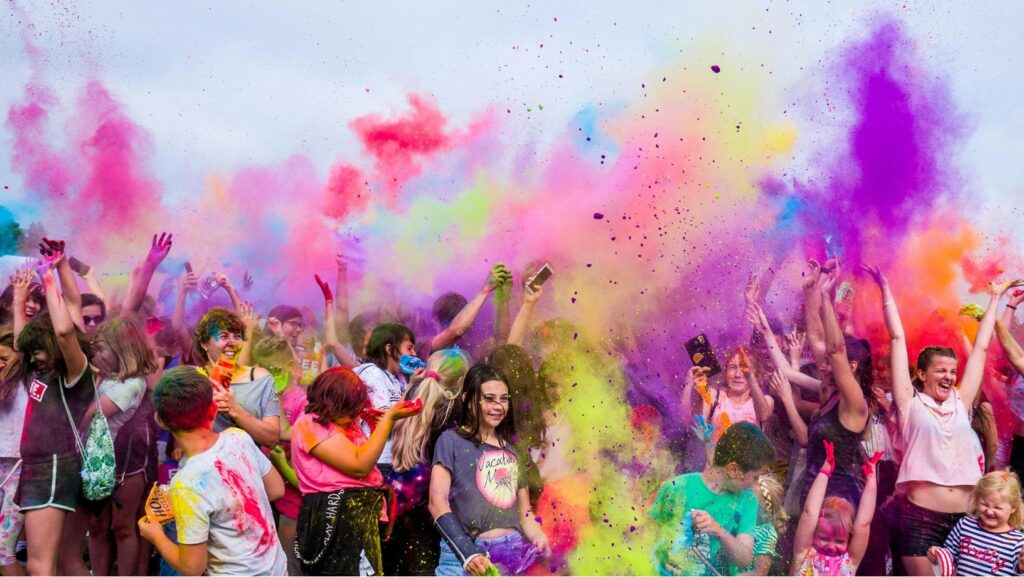 Mensen vieren een kleurrijk festival door poederverf in de lucht te gooien tijdens een feestelijk evenement.